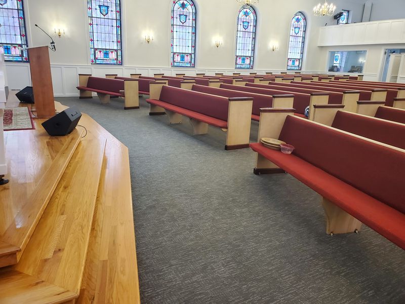 Church sanctuary with rows of red-cushioned pews and freshly cleaned carpet